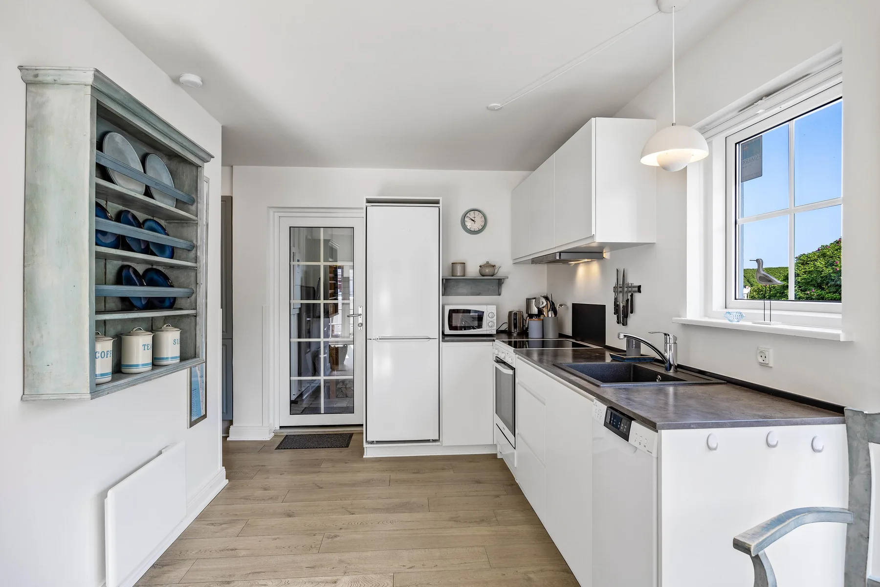 Una cocina luminosa con armarios blancos y una encimera.