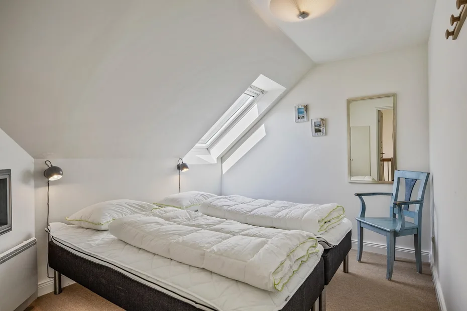 Un dormitorio con camas bajo un techo inclinado y una claraboya.