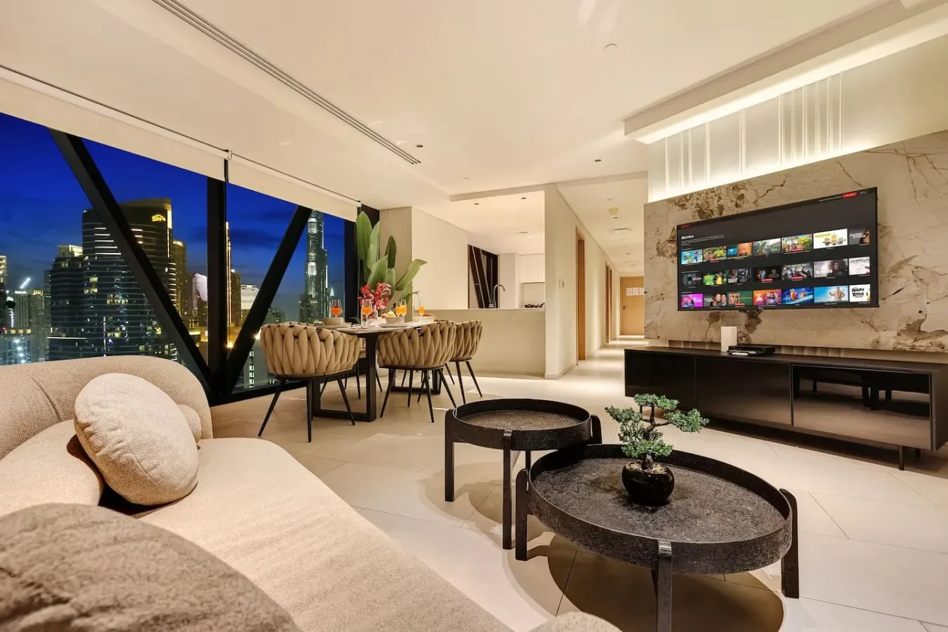 Una sala de estar moderna con comedor y vistas a la ciudad por grandes ventanales.