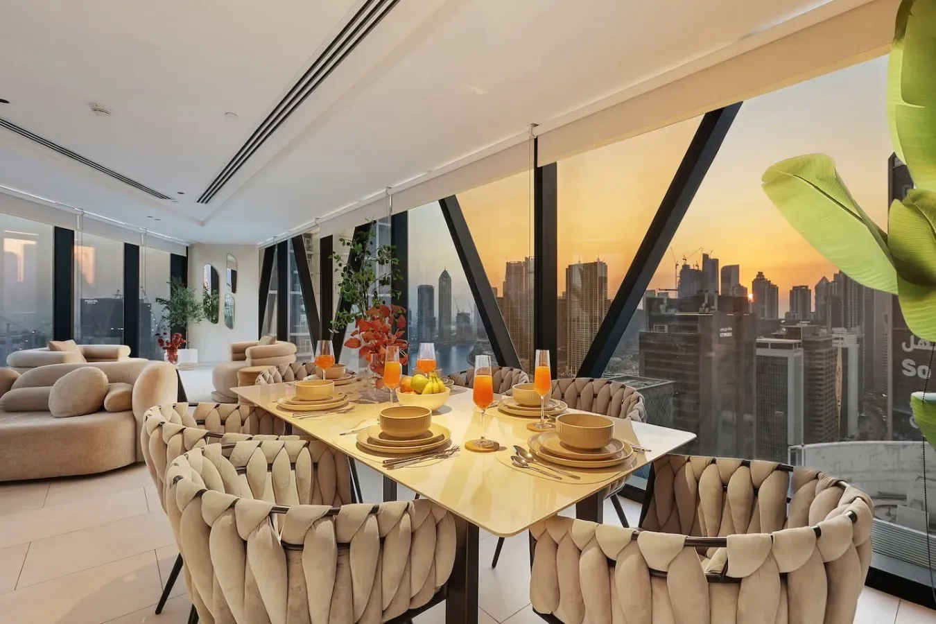 Comedor con una mesa puesta junto a ventanales con vistas a la ciudad.