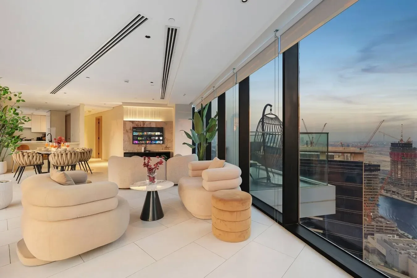 Una sala luminosa con asientos redondeados y ventanales de piso a techo con vistas a la ciudad.