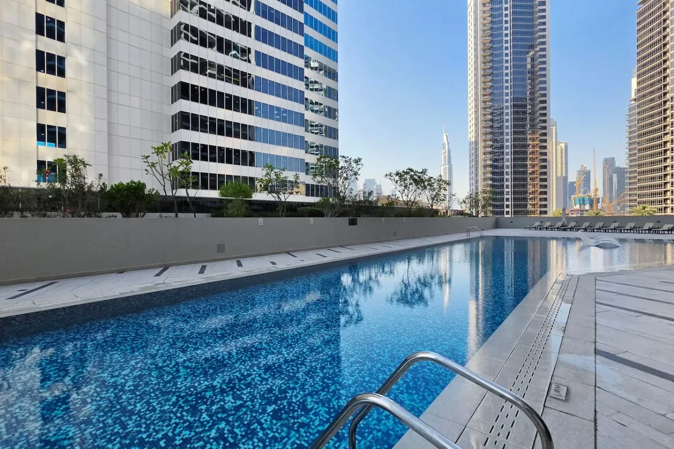 Una piscina al aire libre está rodeada de edificios altos modernos.
