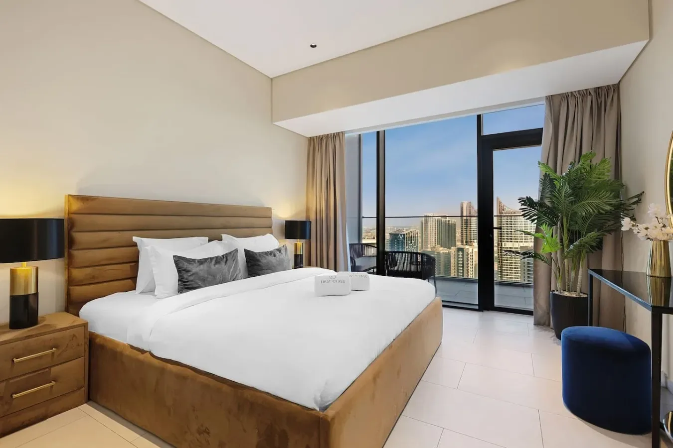 Un dormitorio con una cama junto a ventanales con vistas a edificios de la ciudad.
