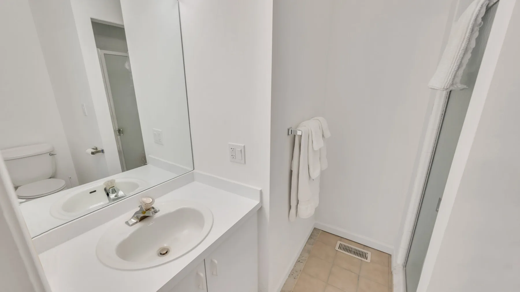 A bathroom vanity with a sink and mirror beside a shower.