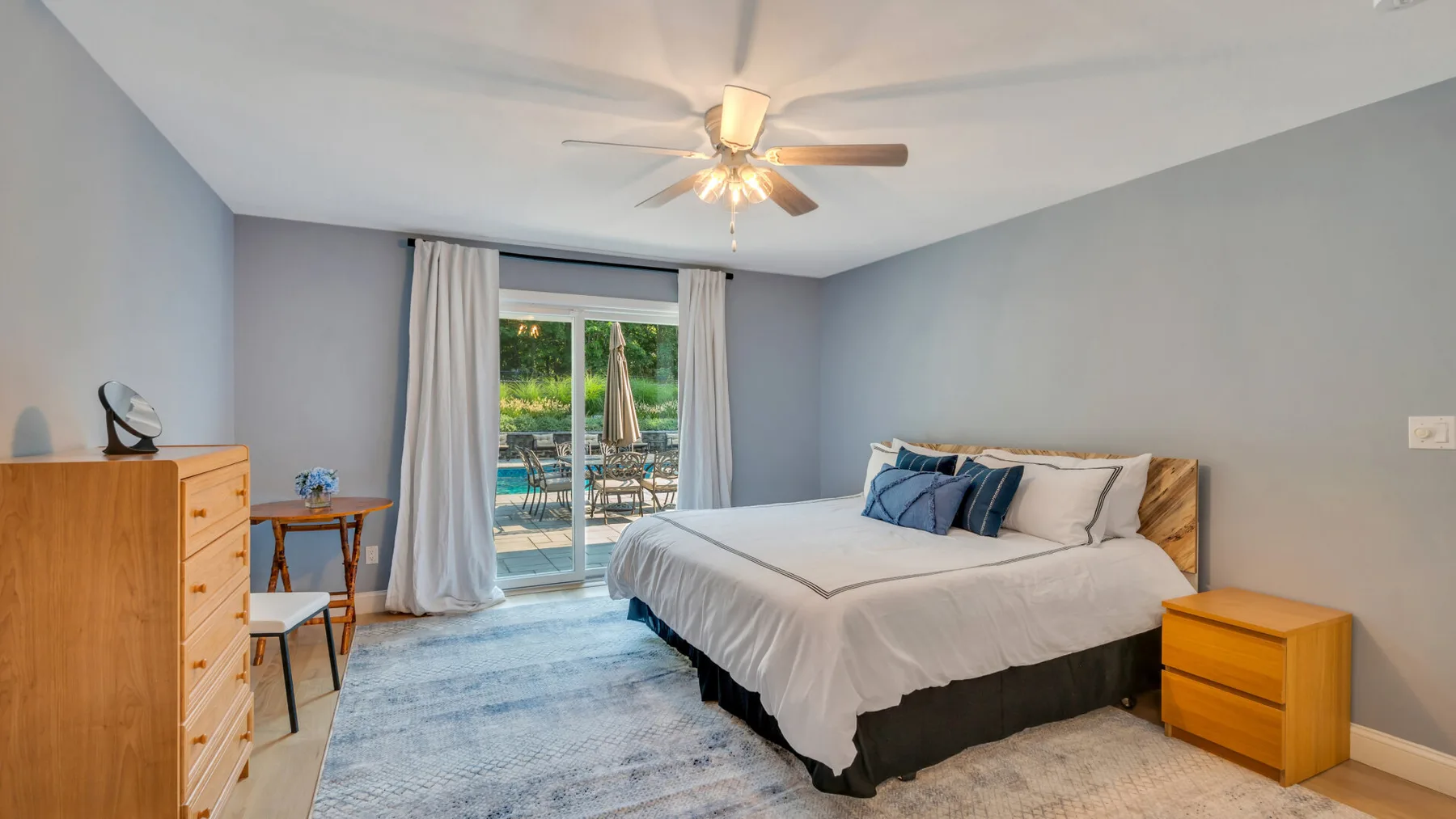 A bedroom with a bed, bedside tables, and sliding glass doors opening to a balcony.