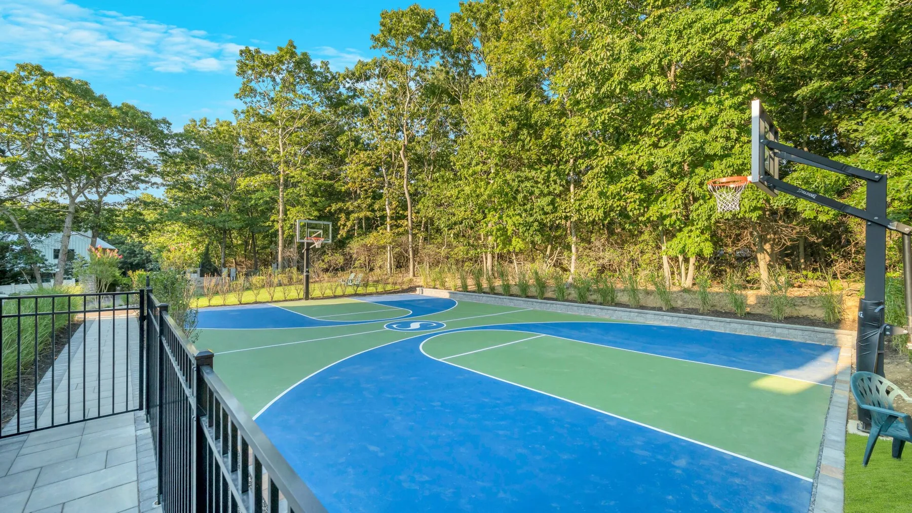 An outdoor basketball court with blue and green painted playing surfaces and hoops.