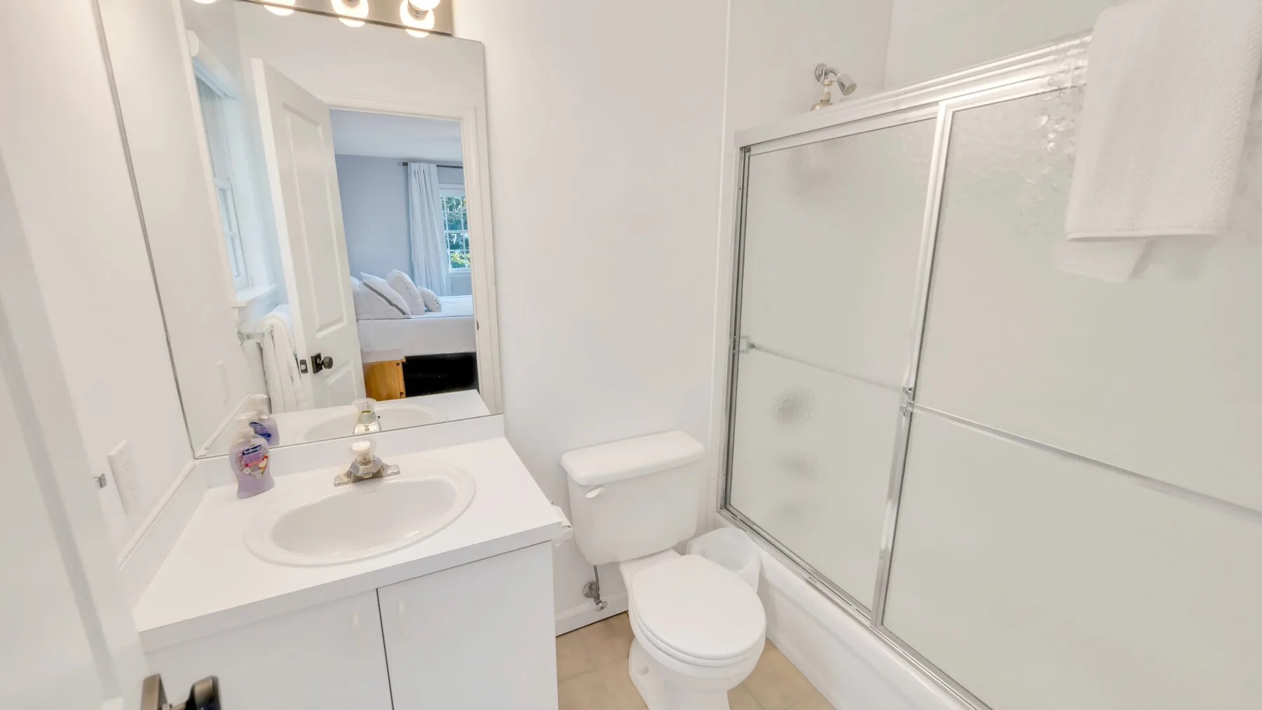 A bright bathroom with a sink, toilet, and shower.