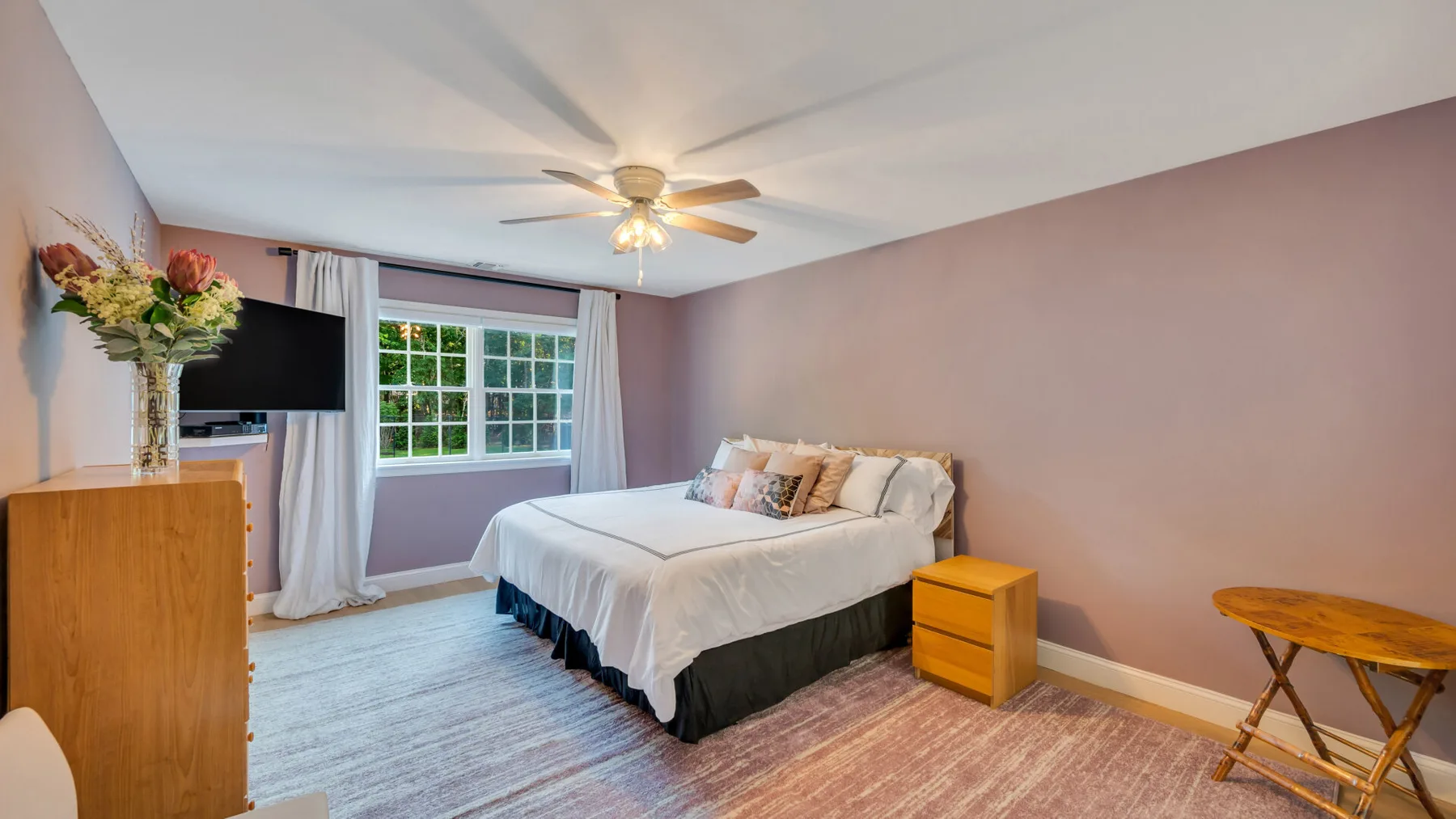 A bedroom with a bed, a window, and a ceiling fan.