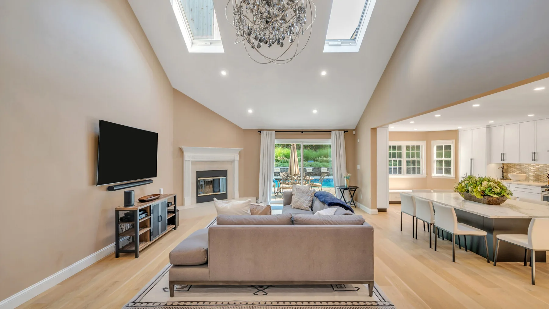 A bright open-plan living room and kitchen with a large seating area and skylights.