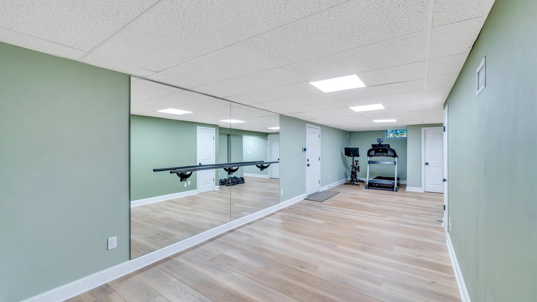 An exercise room with mirrored walls and fitness equipment at the far end.