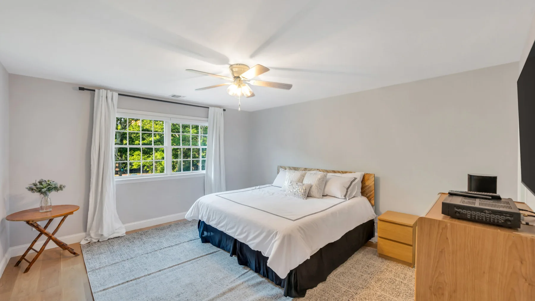 A bedroom with a bed, a window, and a wooden dresser.