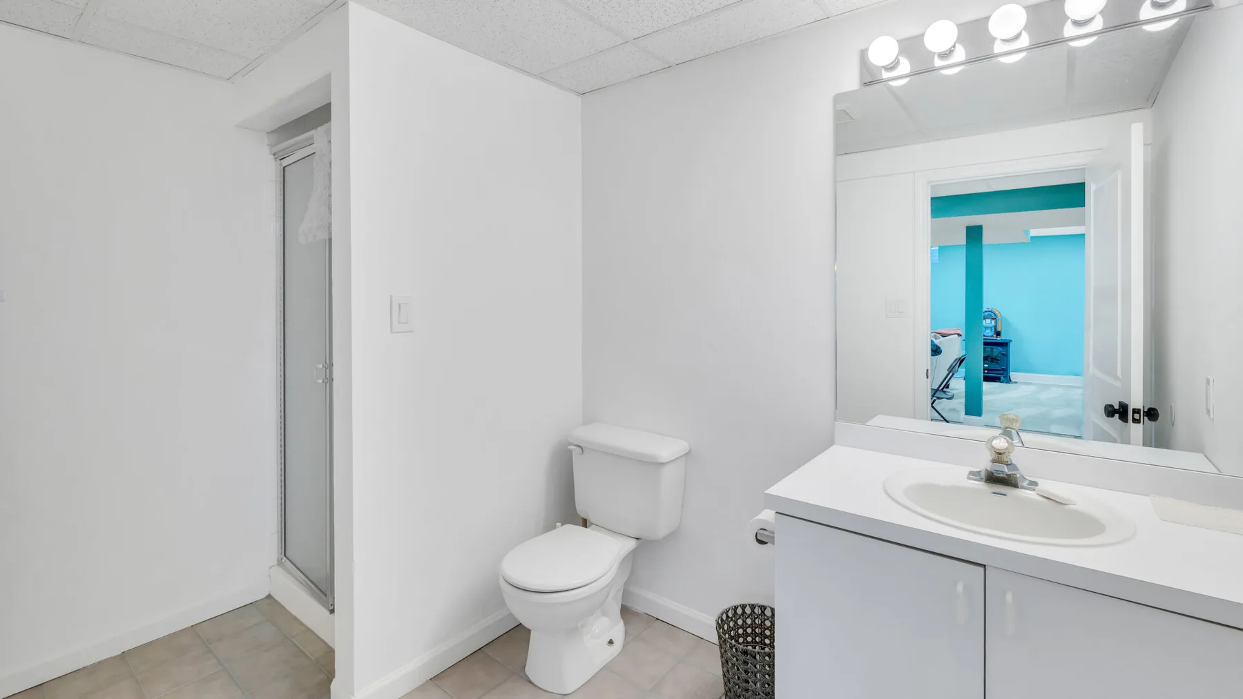 A bathroom with a toilet, vanity, and mirror.