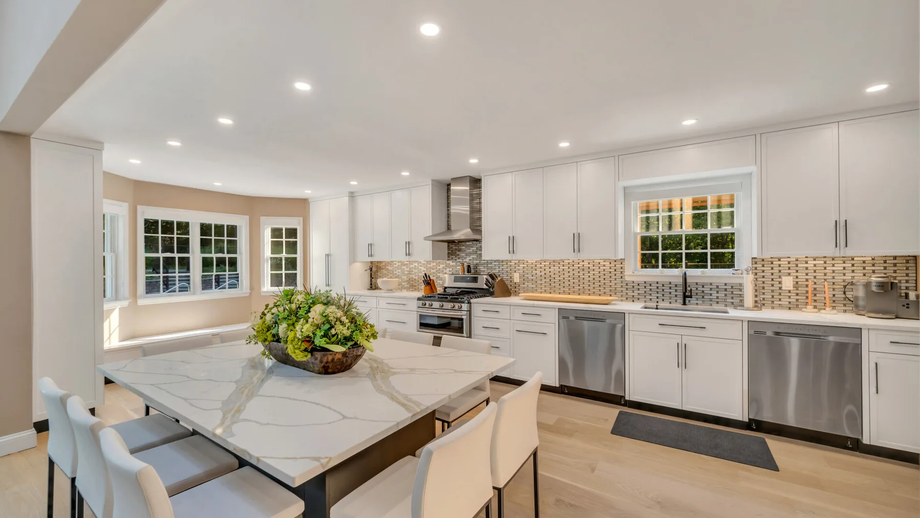 A bright kitchen with a large island, pale cabinetry, and stainless steel appliances.
