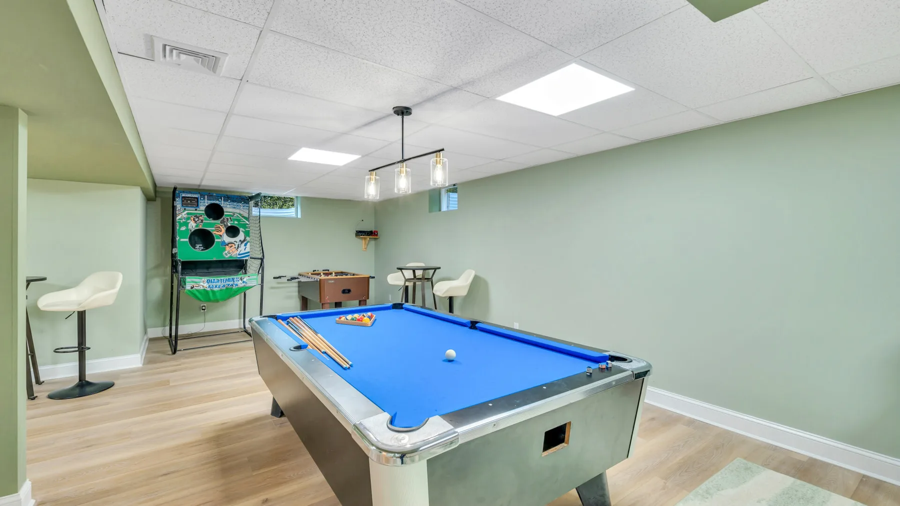 A game room with a blue pool table and arcade machine.