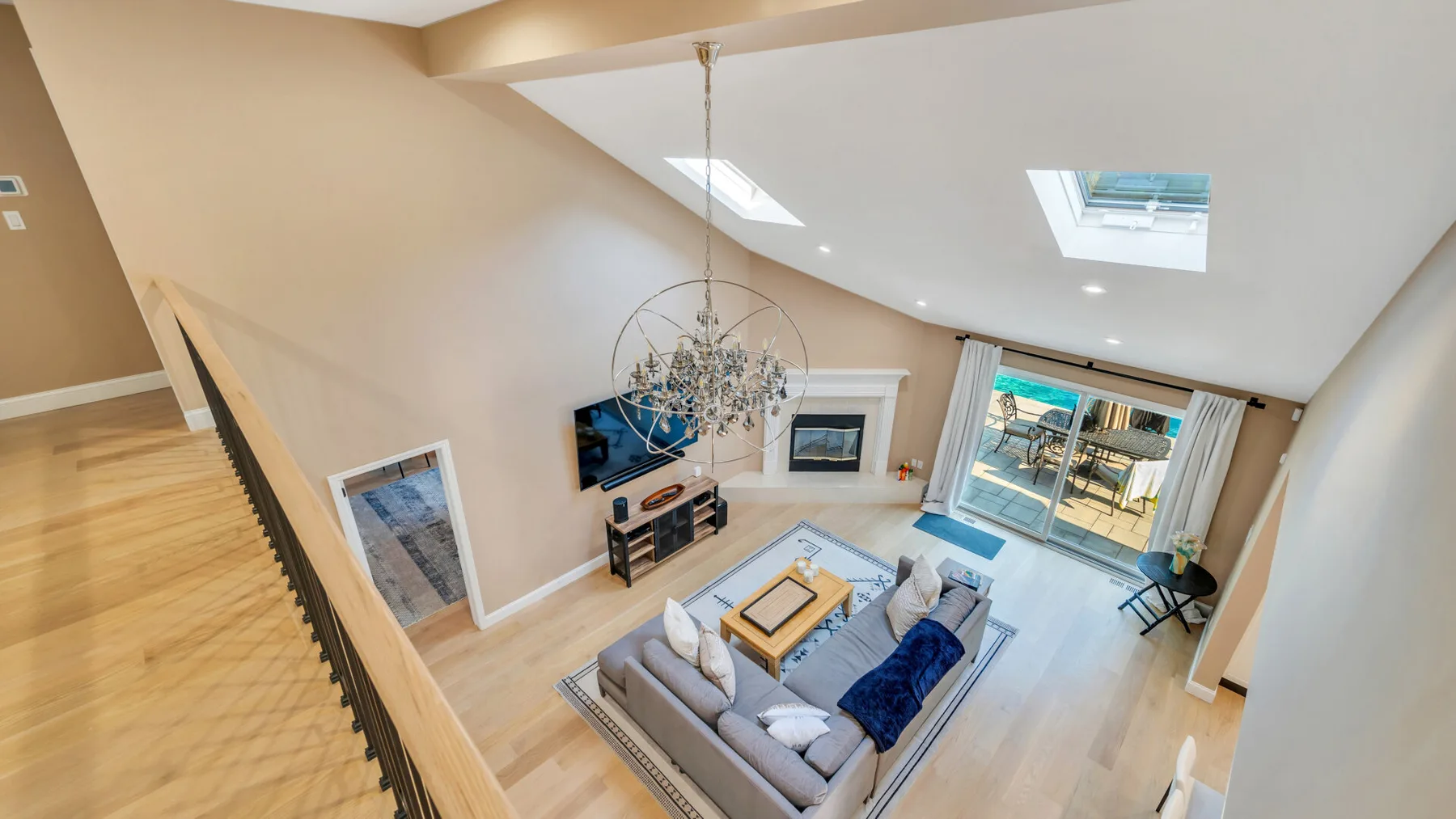 A bright open living room with a seating area, fireplace, and large windows.