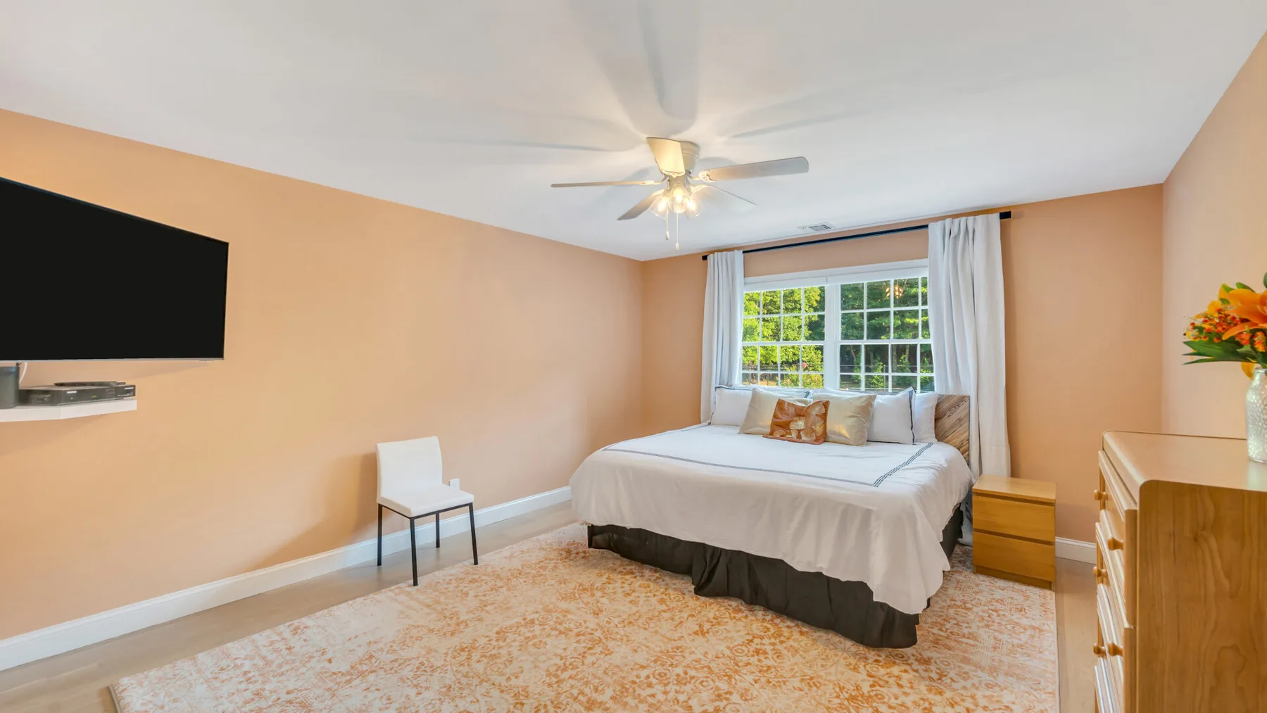 A bedroom with a bed, a window, and a light-colored rug.