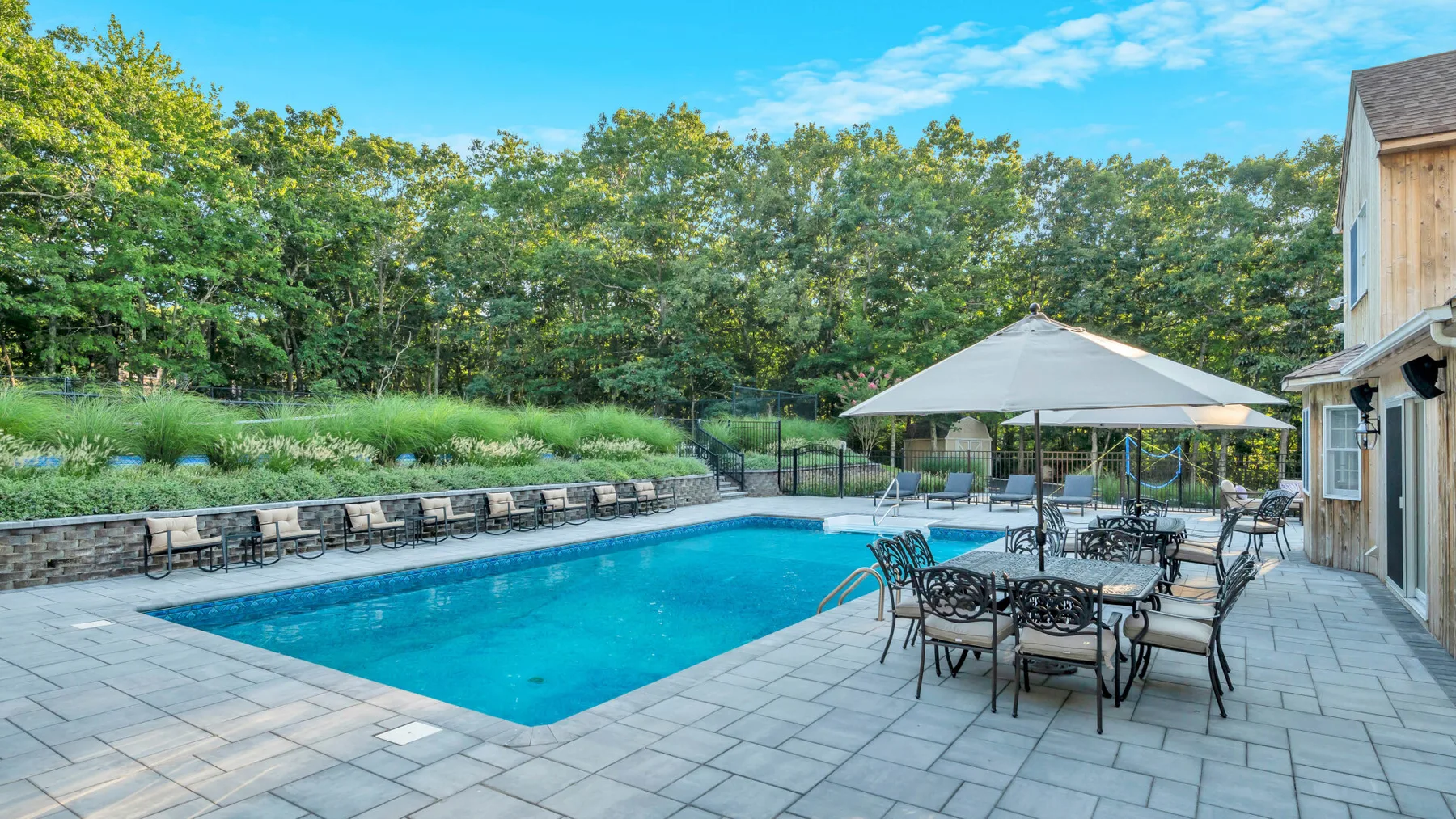 An outdoor pool and patio seating sit beside a landscaped garden.