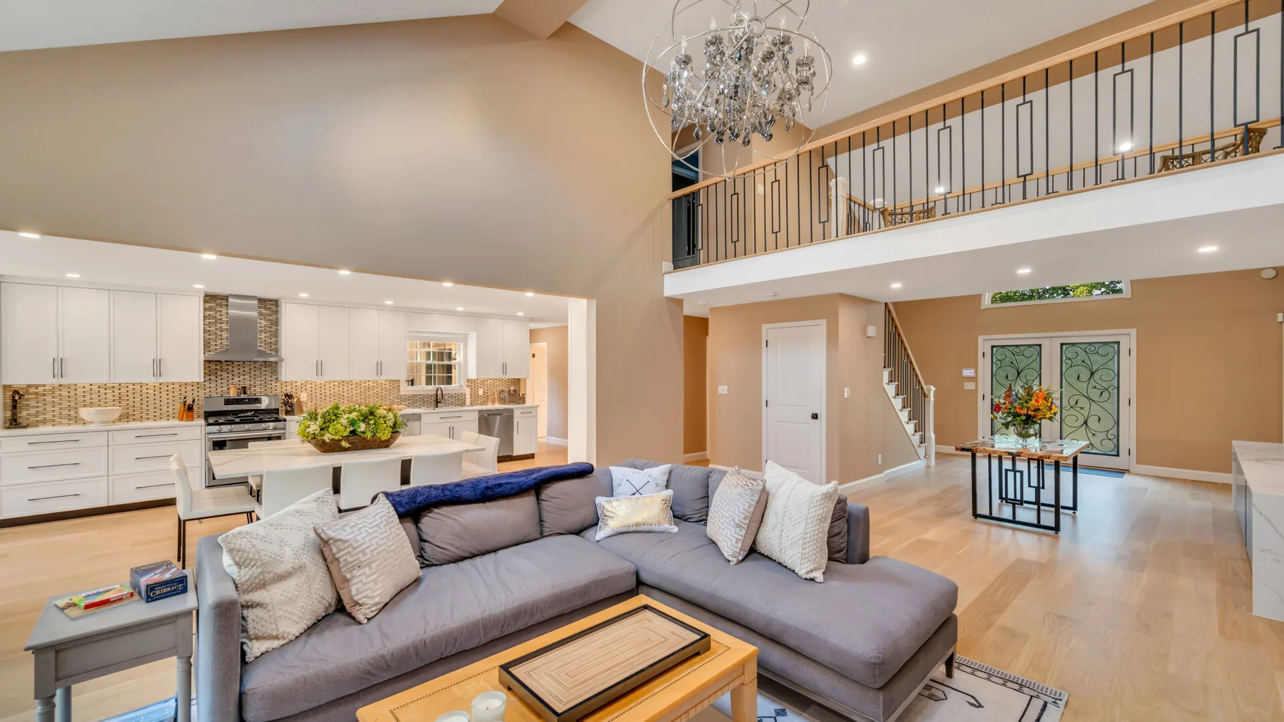 An open-plan living room and kitchen with a gray sectional and an island.
