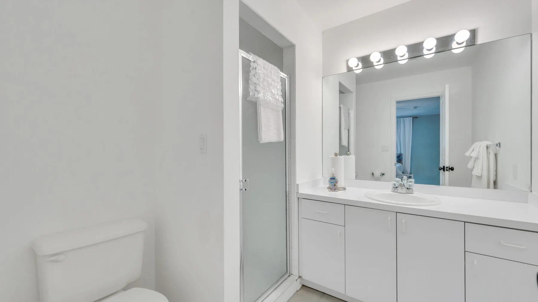 A bright bathroom with a long vanity and a large mirror.