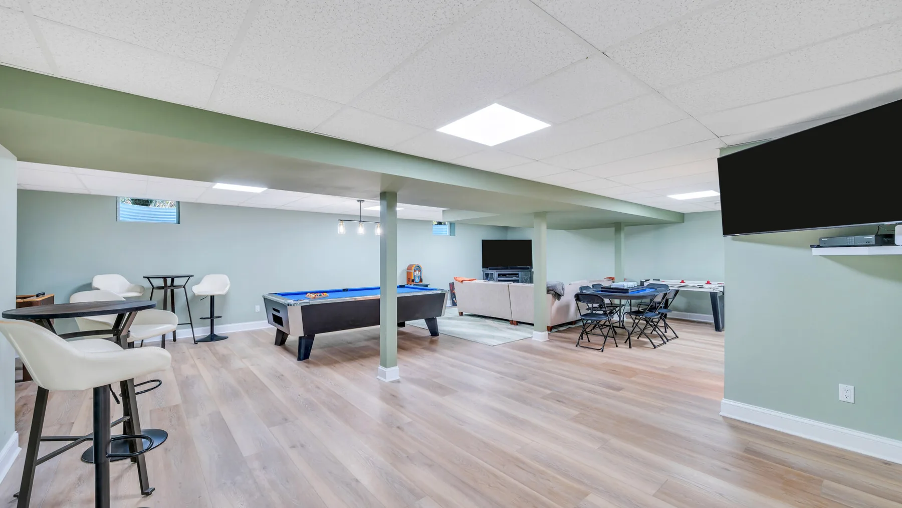 A recreation room with seating, a pool table, and a game table.