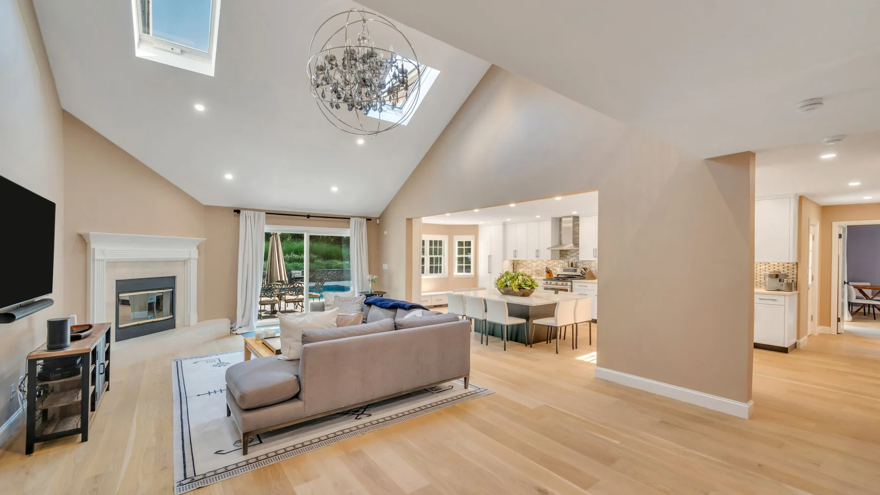 A bright open-plan living room with a seating area and kitchen.
