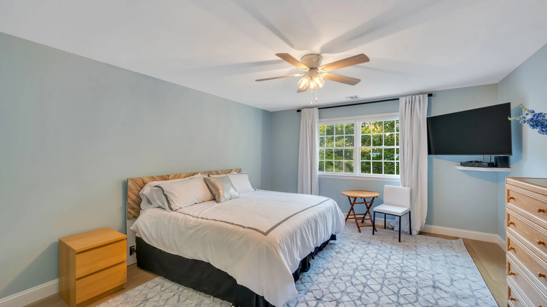 A bedroom with a bed, a window, and a ceiling fan.