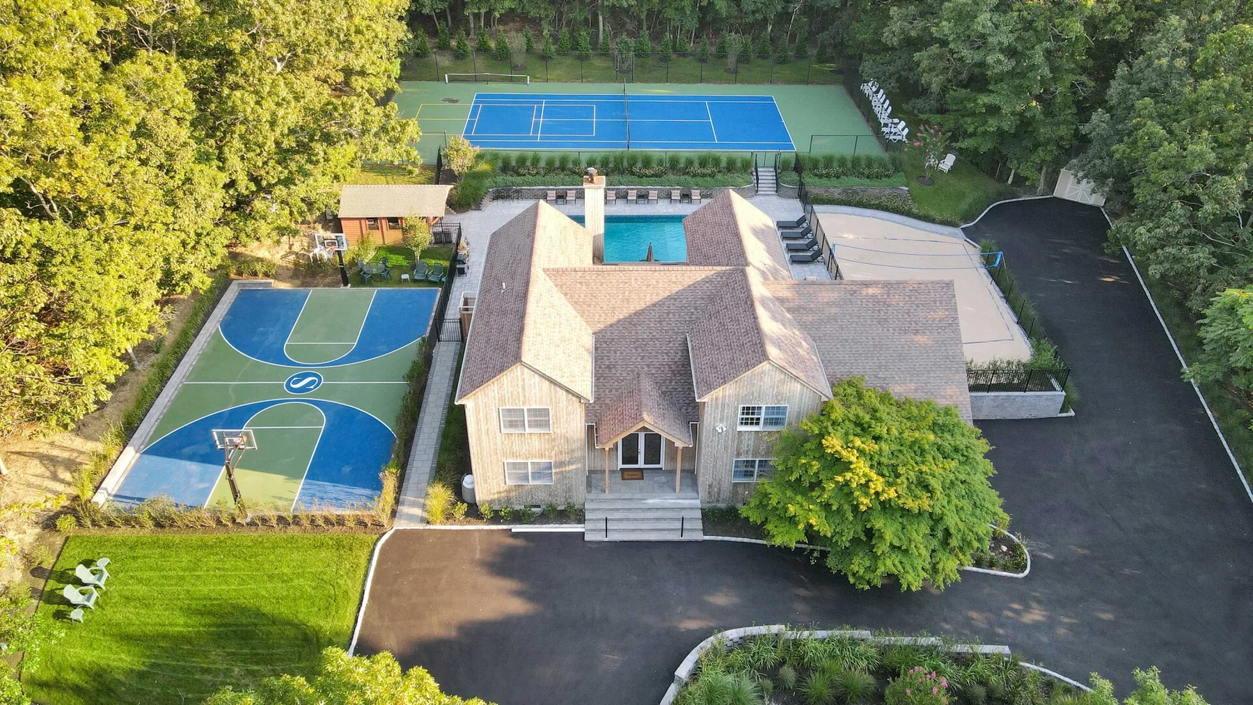 Aerial view of a house with outdoor basketball and tennis courts.