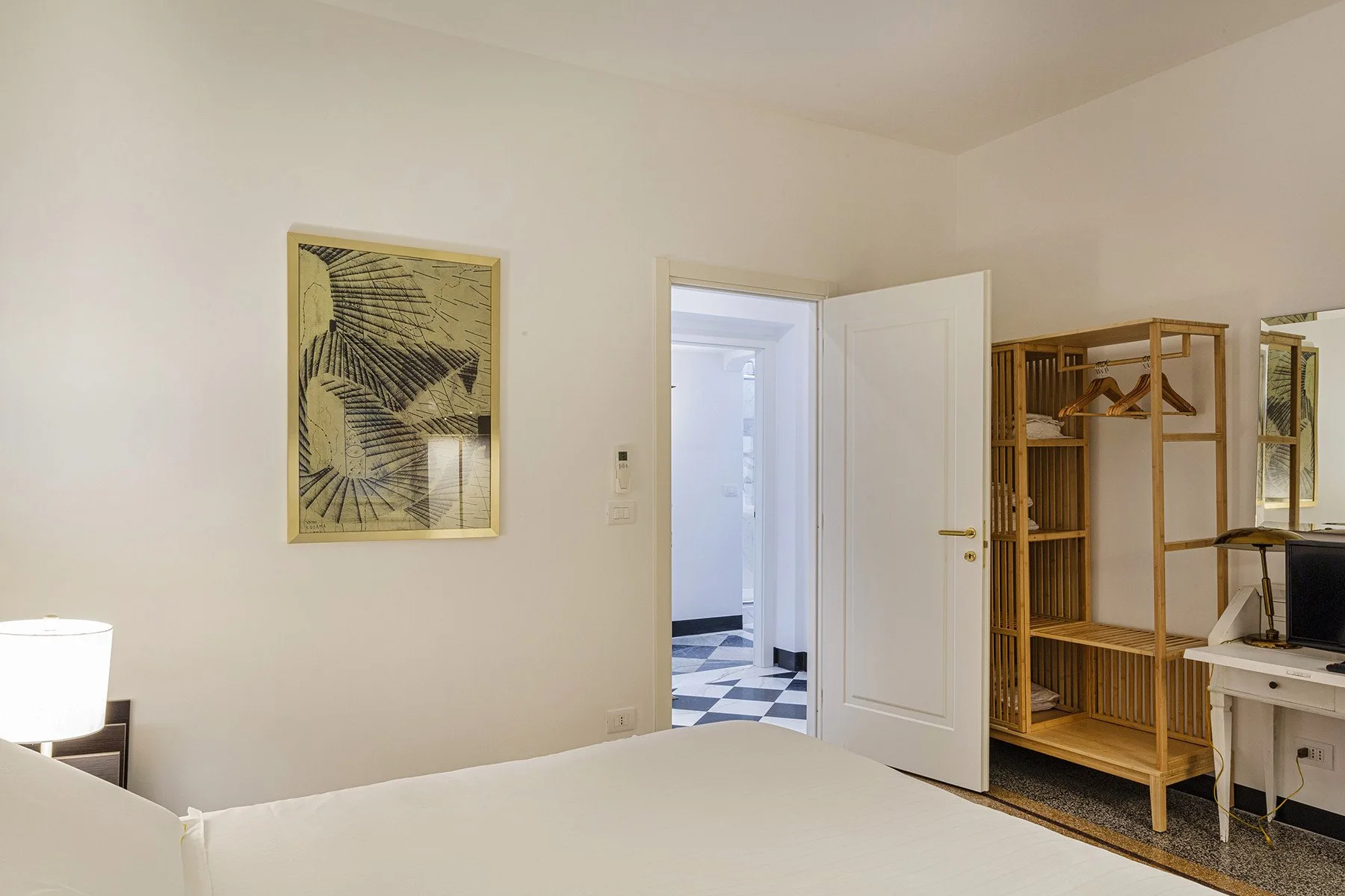 A bedroom with a bed, wall art, and an open doorway to a tiled hallway.