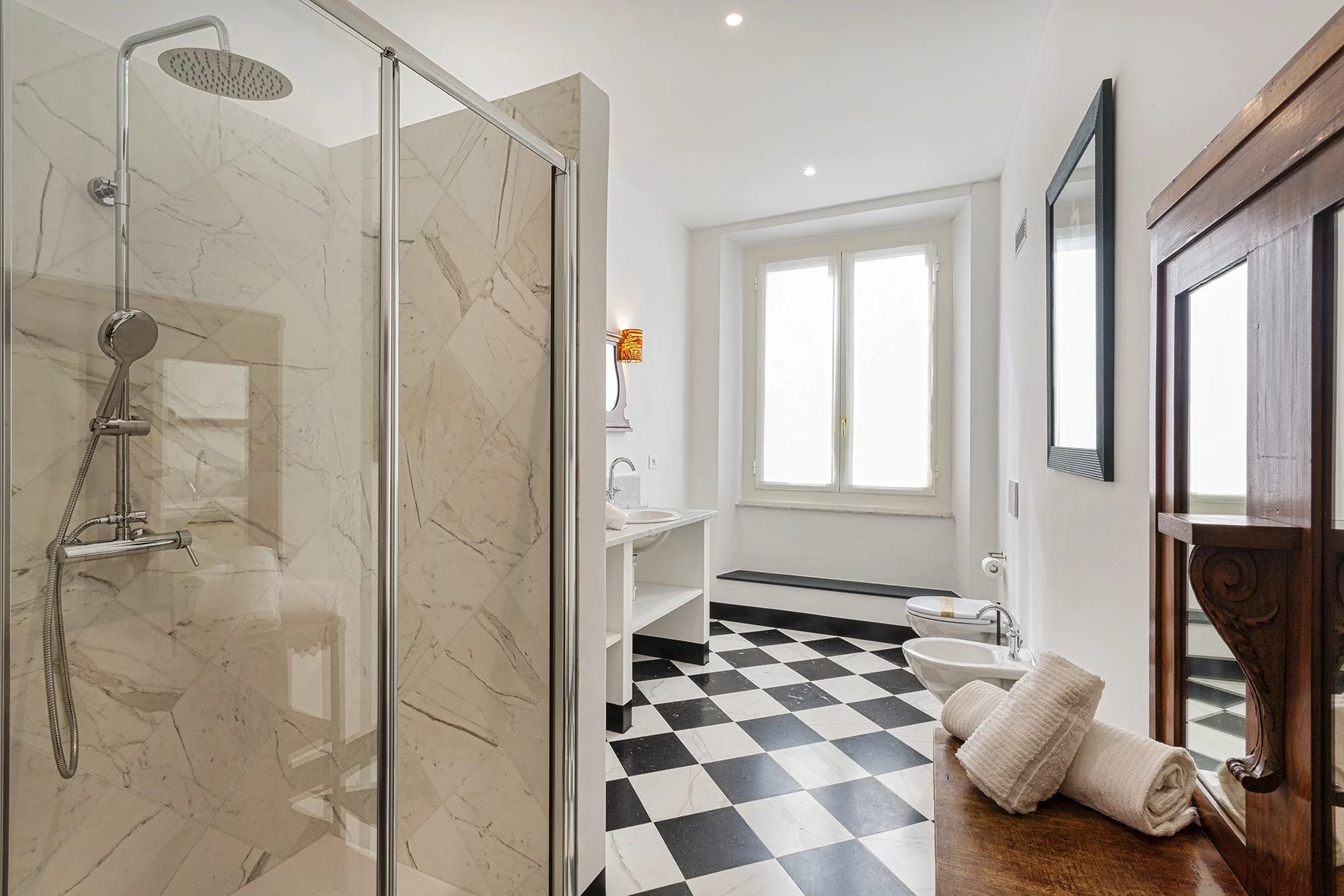 A bright bathroom with a glass shower and black-and-white checkered floor.