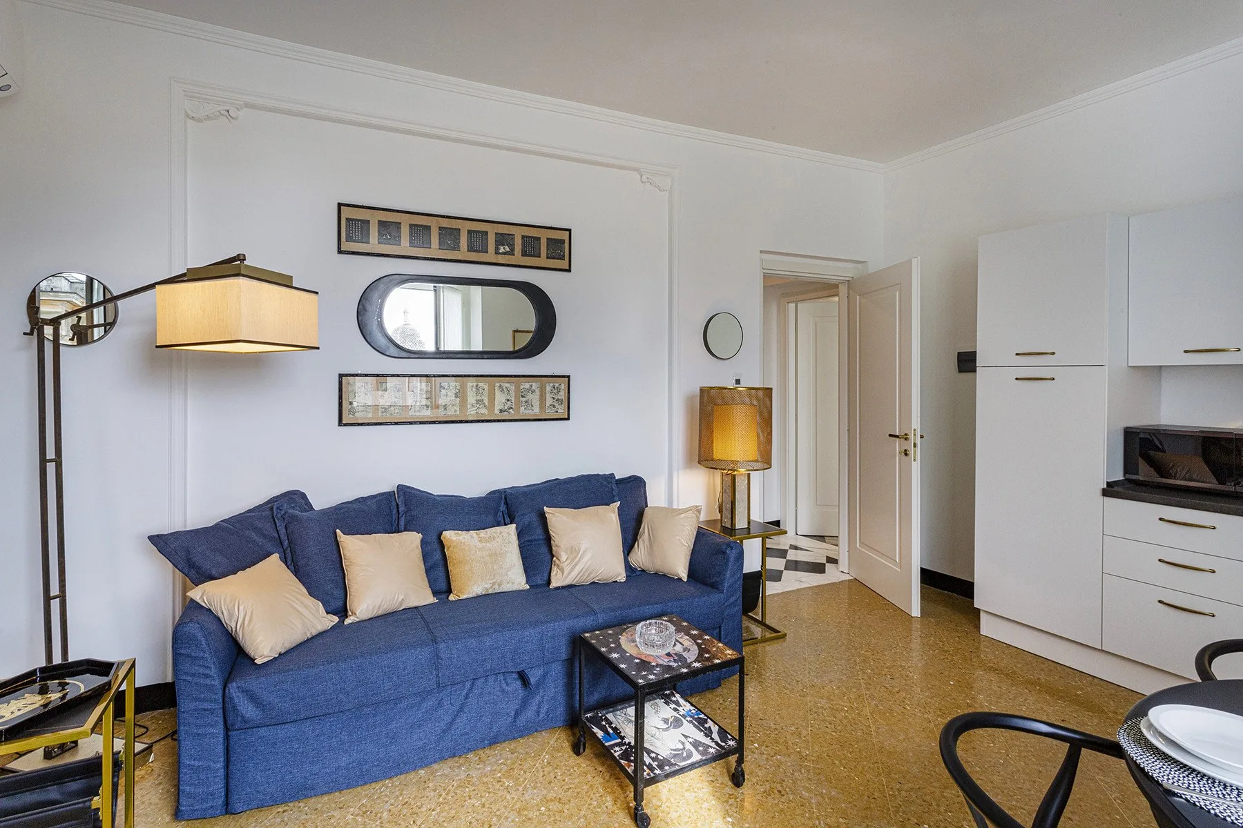 A living room with blue seating, framed artwork, and a small coffee table.