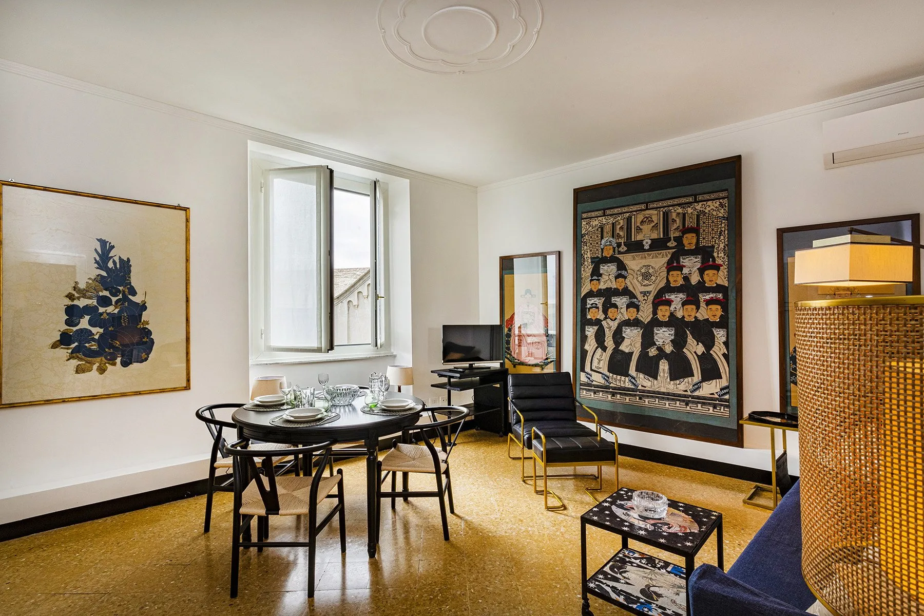 A bright living room with a dining table, seating, and framed artwork.