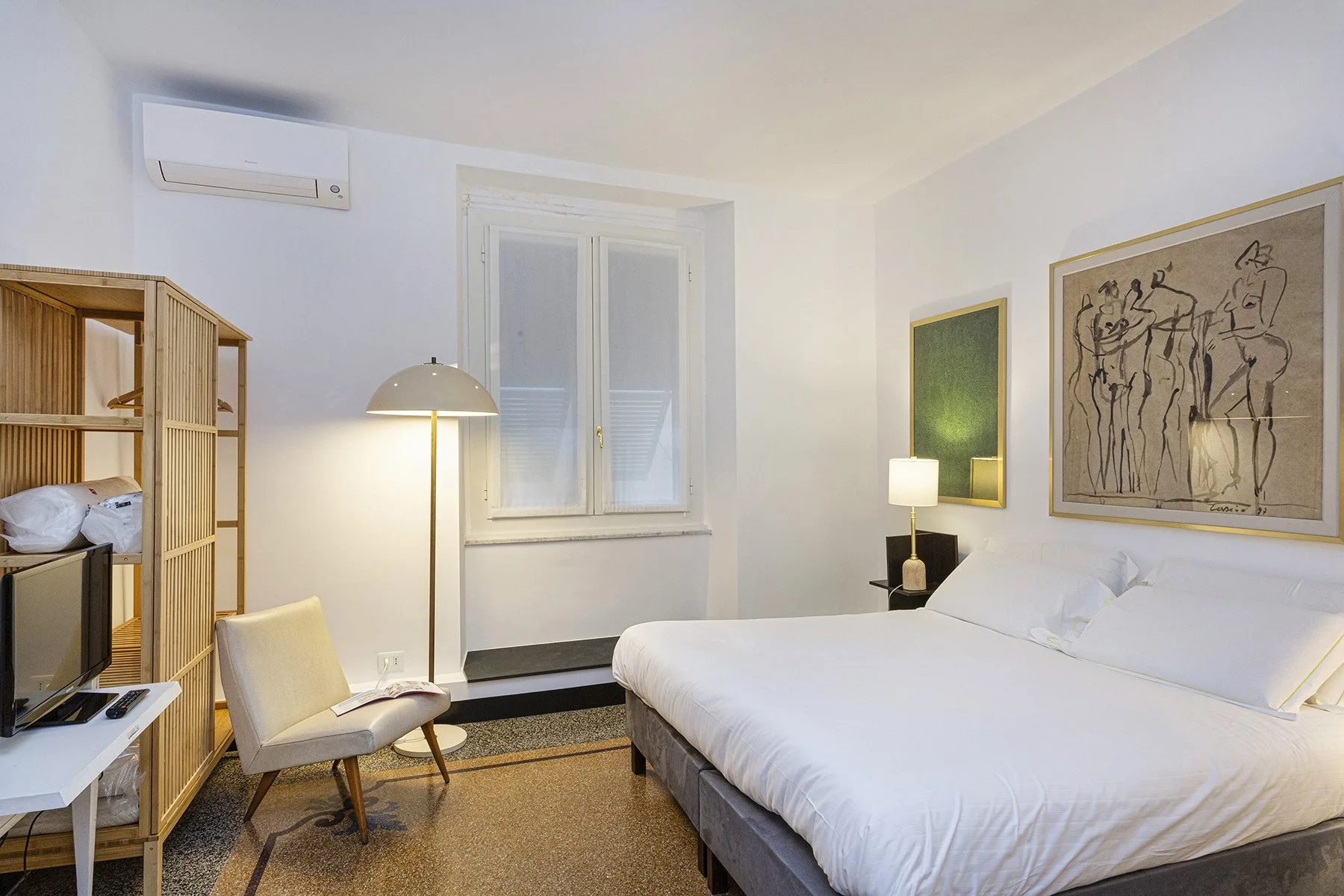 A bedroom with a bed, a window, and a reading chair.