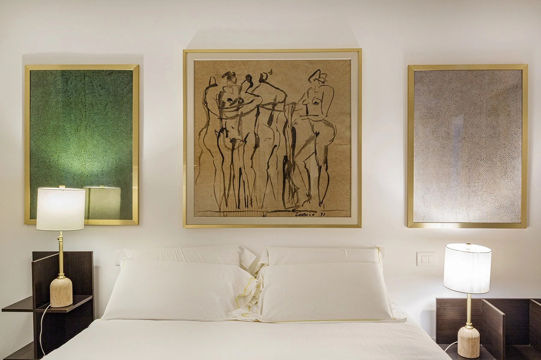 A bedroom with a bed beneath three framed artworks.