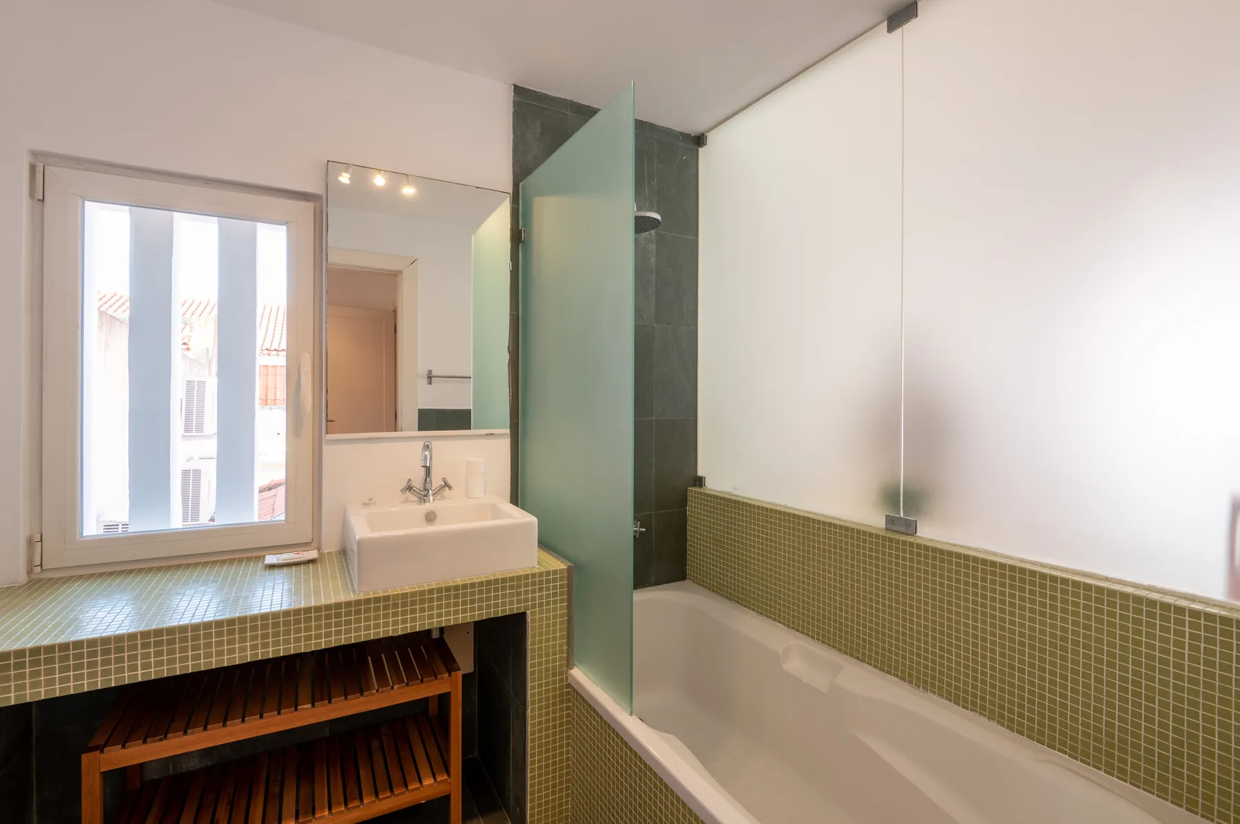 A bathroom with a bathtub, sink, and window.