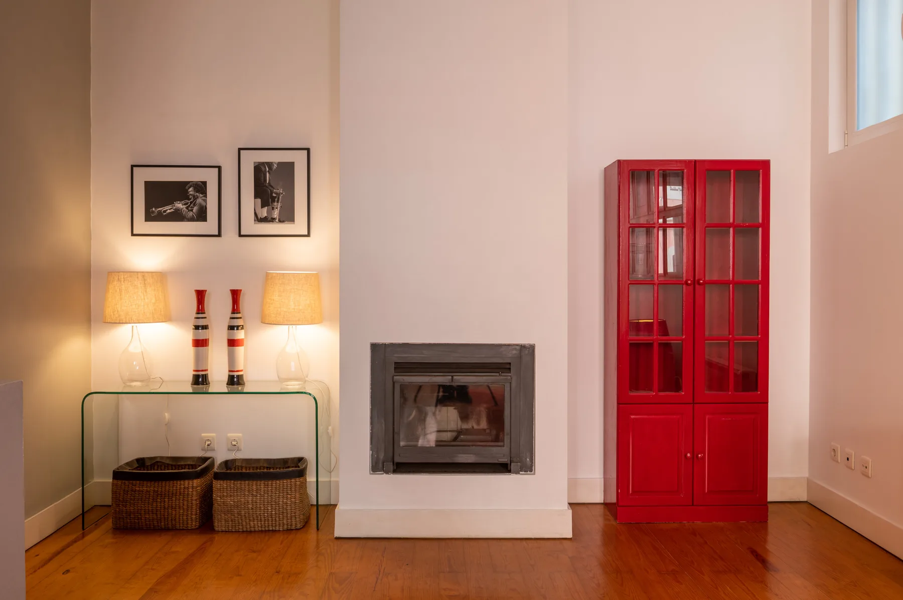 Living room with a fireplace, glass console, and red display cabinet.