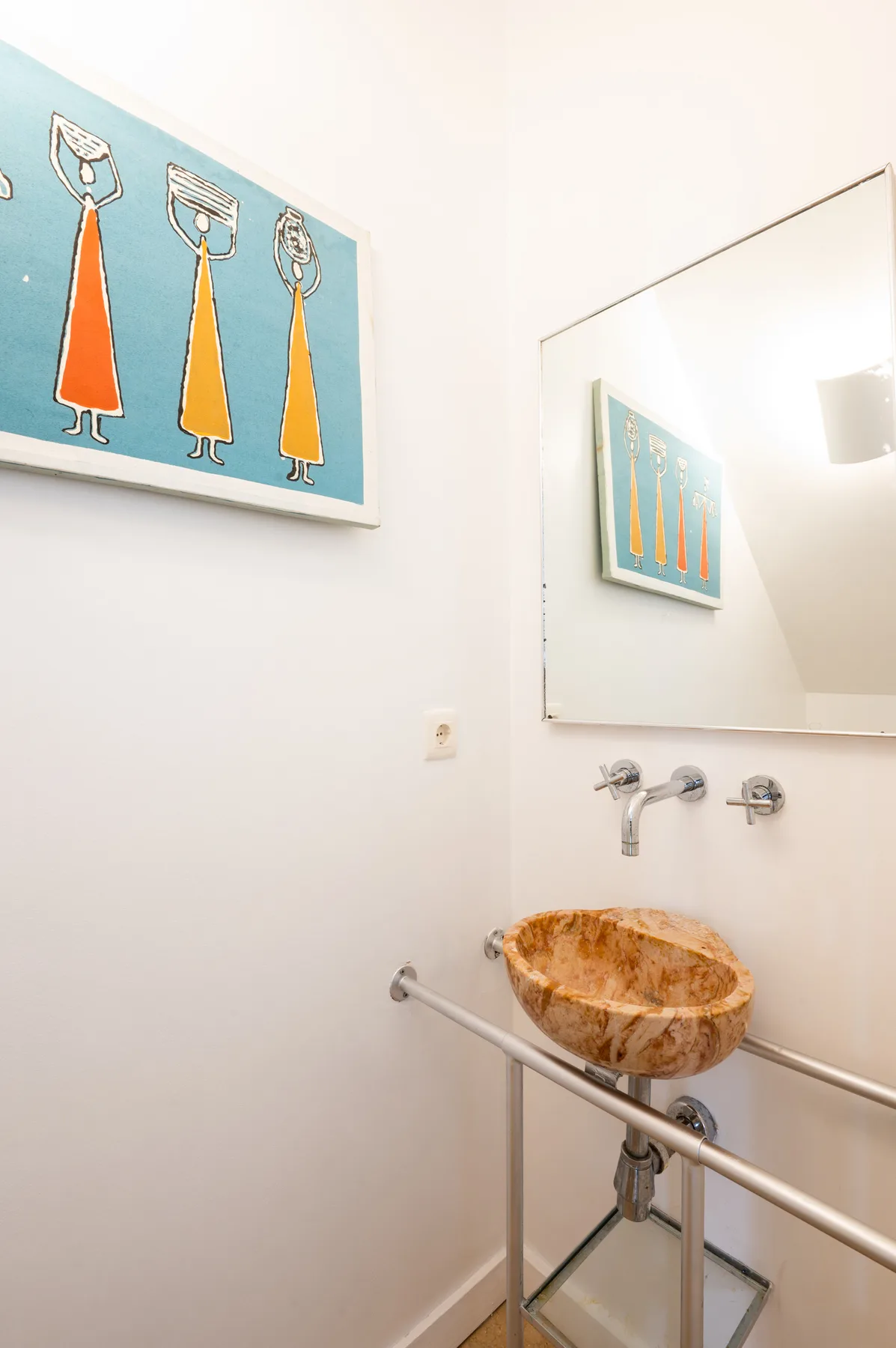 A bathroom with a stone vessel sink, wall mirror, and metal grab bars.