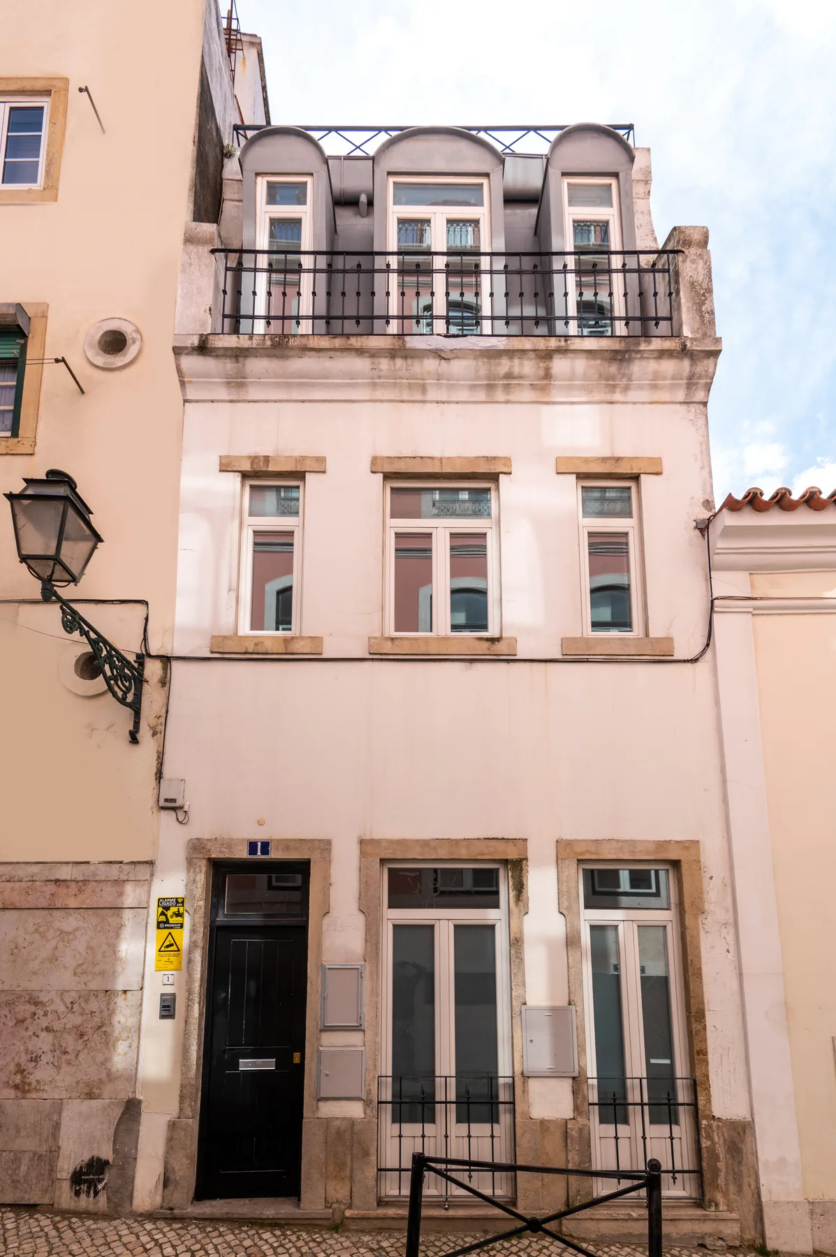 A narrow multistory building facade with tall windows and a small balcony.
