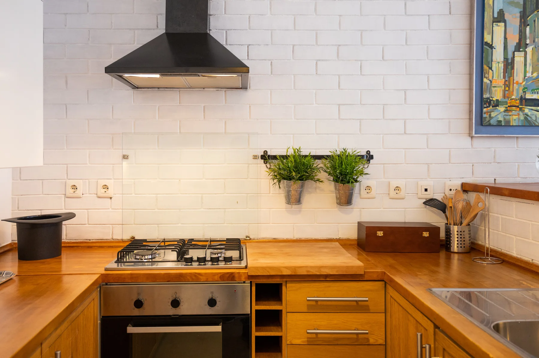 A kitchen with a stovetop, wooden counters, and white tiled walls.