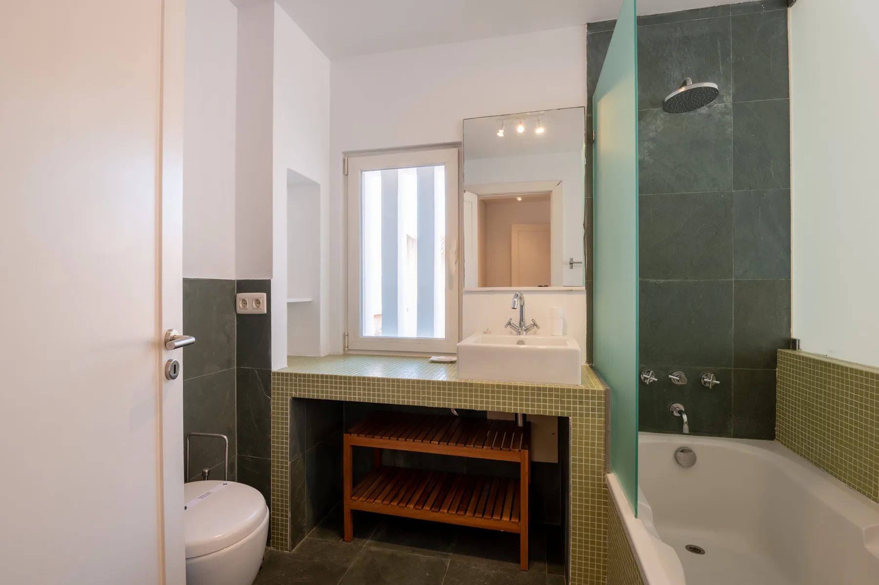 A bathroom with a sink, mirror, and bathtub.