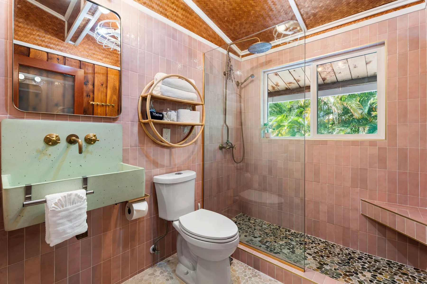 A tiled bathroom with a toilet, sink, and shower area beside a window.