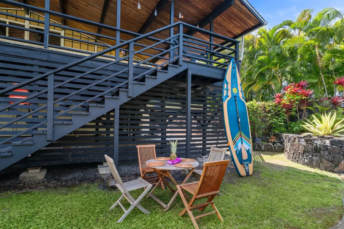 A raised wooden deck overlooks an outdoor seating area beside tropical greenery.