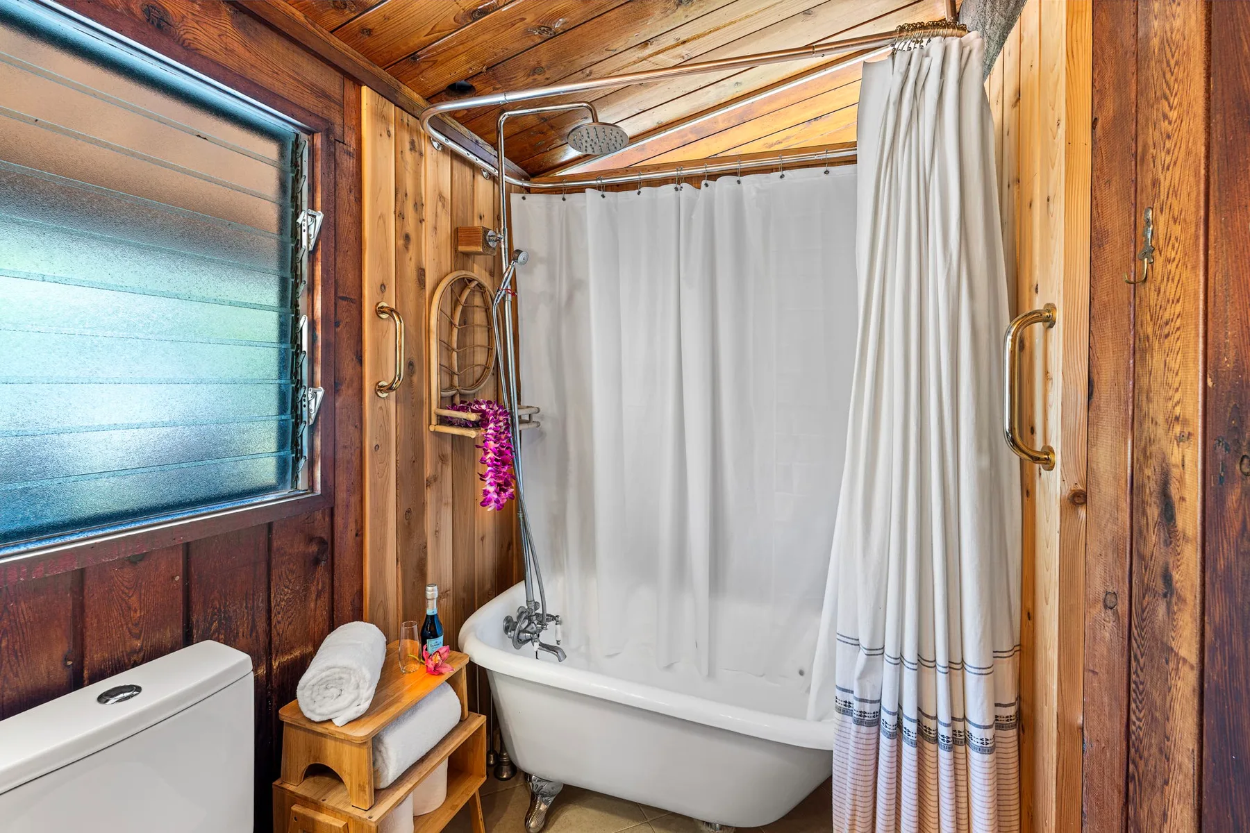 A bathroom with a bathtub, shower curtain, and wood-paneled walls.