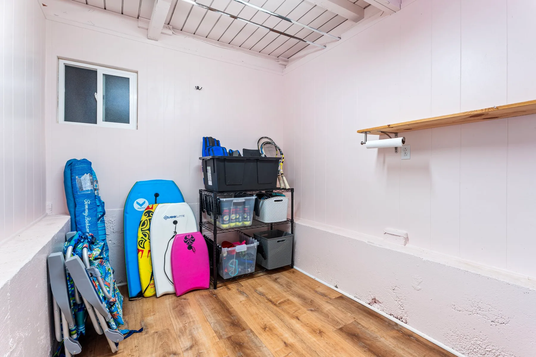 A storage room with beach gear and plastic bins along the wall.