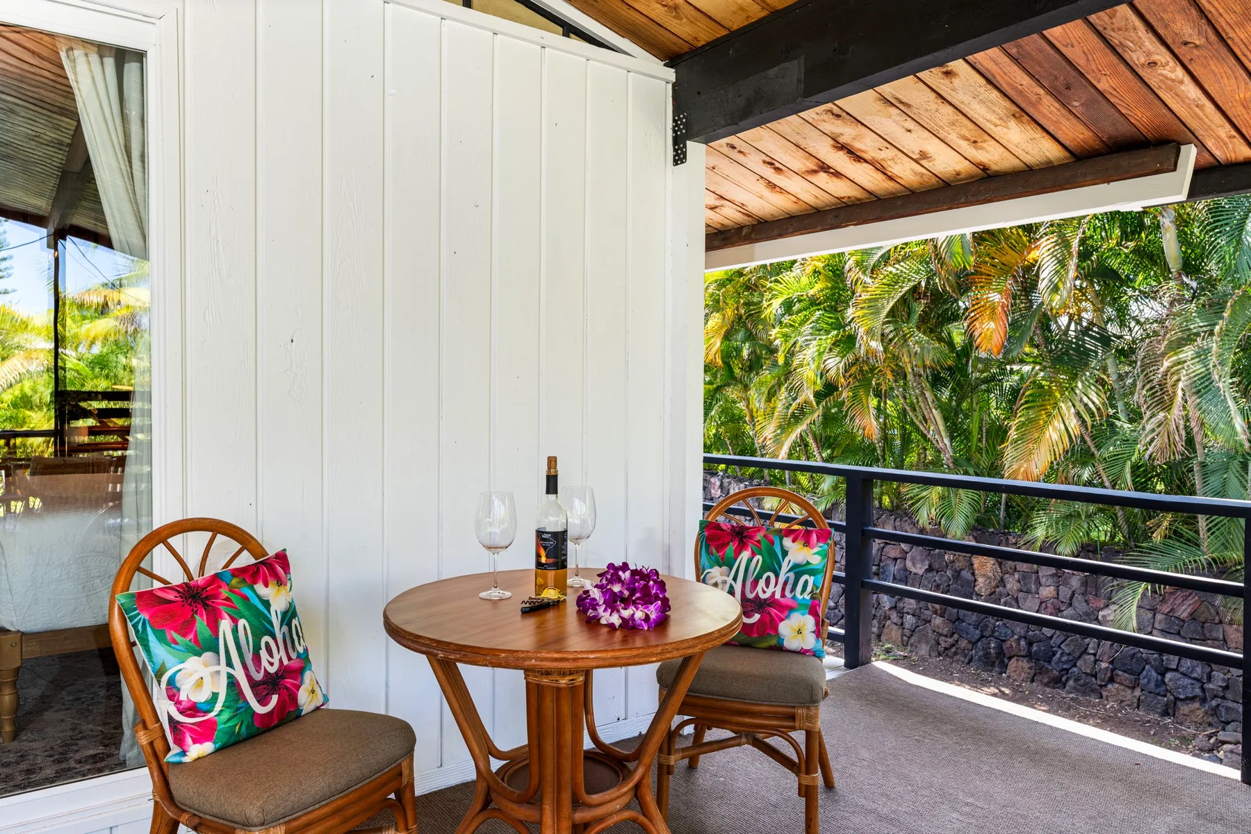 A covered outdoor seating area with a small table overlooking lush greenery.