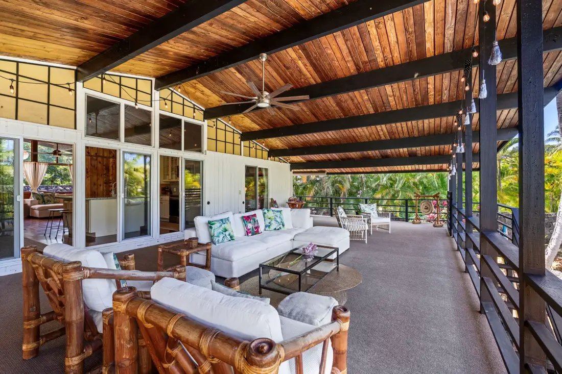A covered outdoor lounge with seating and a view of the garden.