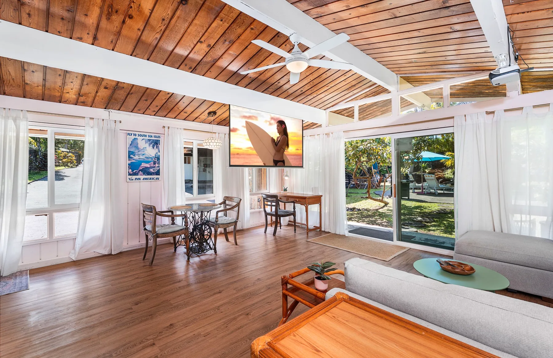 A bright living room with seating, a dining table, and large windows.