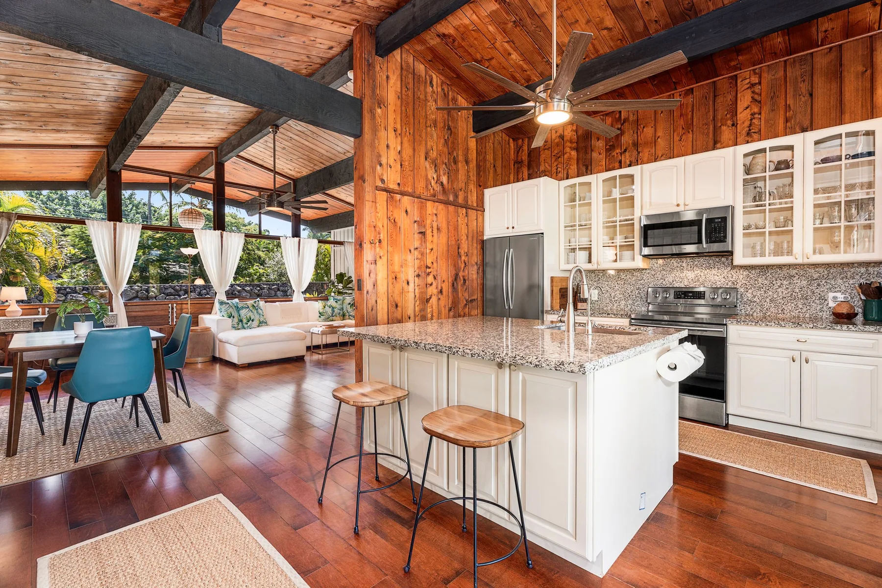 An open-plan kitchen and dining area with a large island and wood-paneled walls.