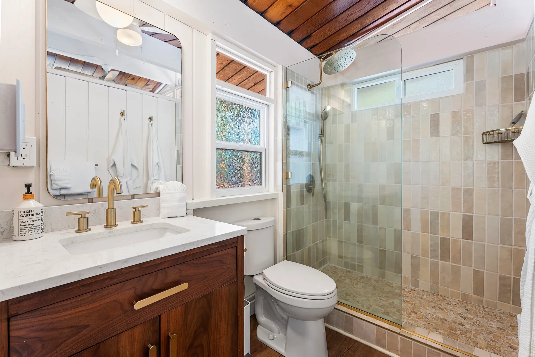 A bathroom with a vanity, toilet, and glass-enclosed shower.