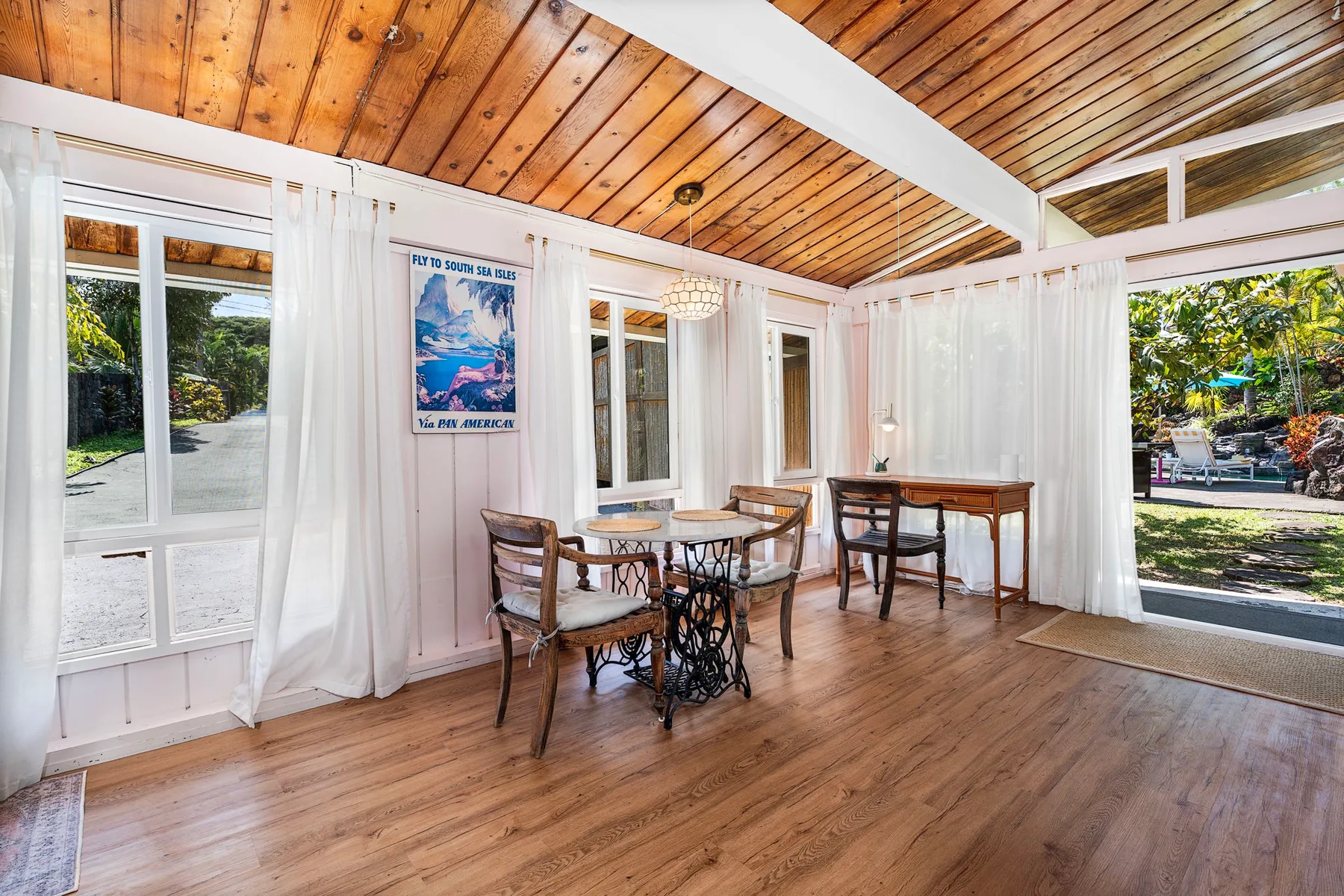 A bright dining area with a small table, seating, and large windows.
