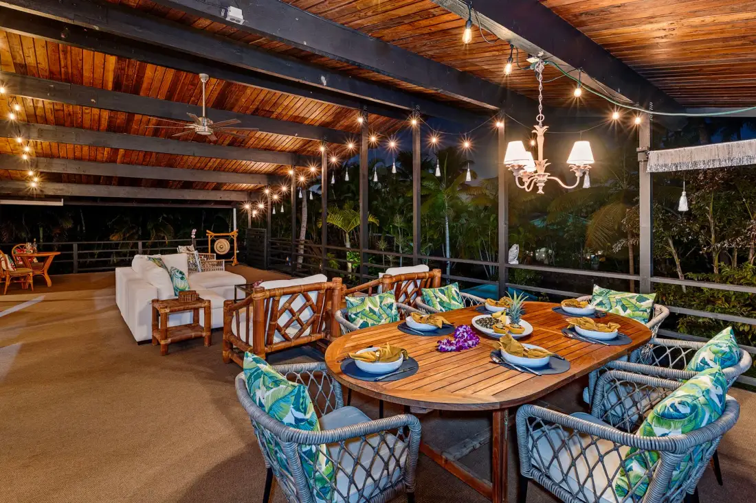 A covered outdoor dining and lounge area with a large wooden table and seating.
